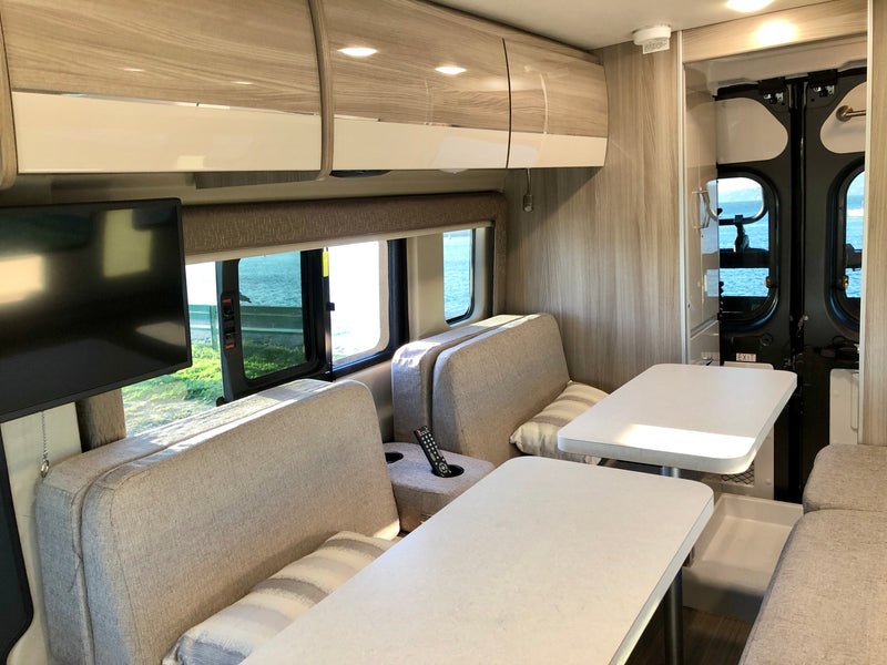 Modern RV rental interior: spacious dinette, comfortable seating, and scenic water views. — photo 11