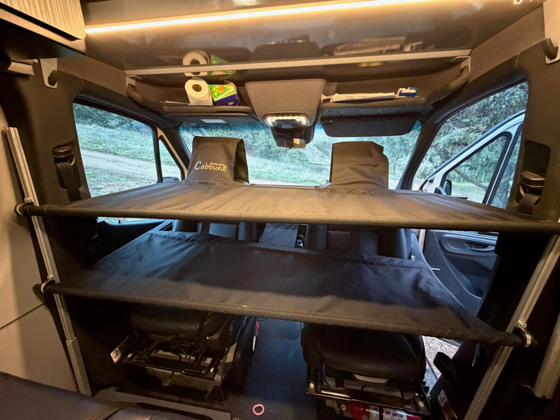 Cab area of an RV rental featuring a "Cabbunk" bunk bed system over the front seats and overhead storage. — photo 10