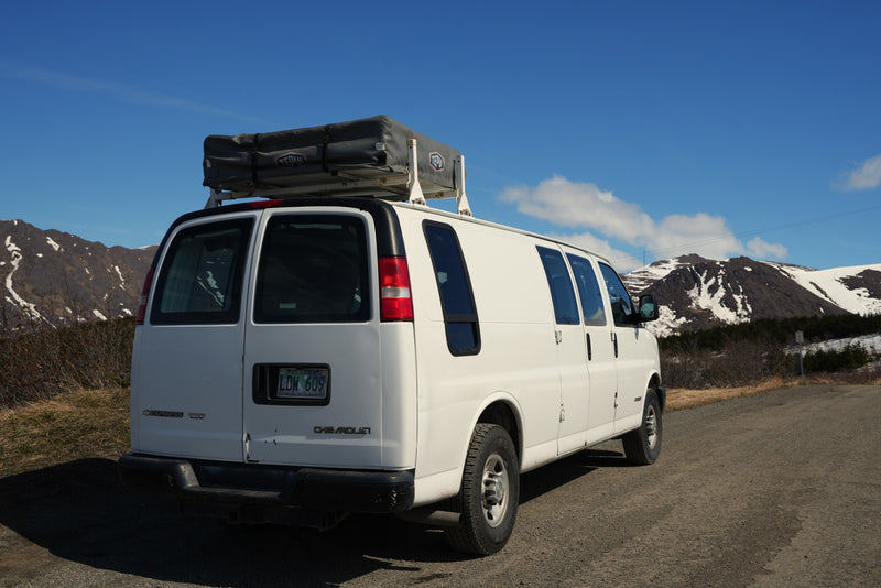 White Chevrolet Express van with a rooftop tent, ideal for an RV rental adventure on scenic mountain roads. — photo 3