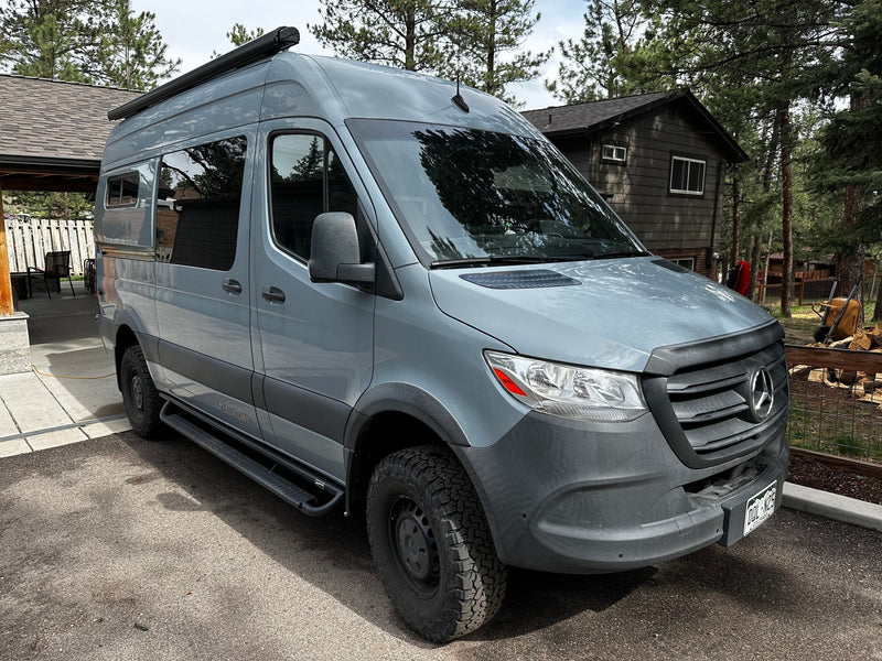 Gray Mercedes Sprinter adventure van, a perfect rv rental, parked near a cabin. Explore van life travel & outdoor experiences. — photo 7