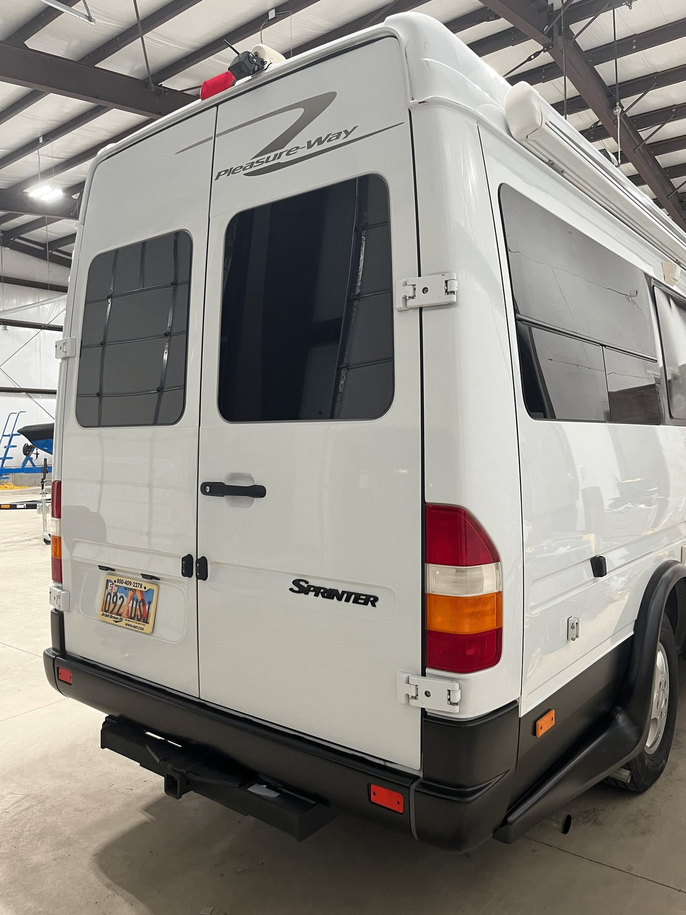 Rear view of a white Pleasure-Way Sprinter RV rental, showing tinted windows, tail lights, and a tow hitch. — photo 11