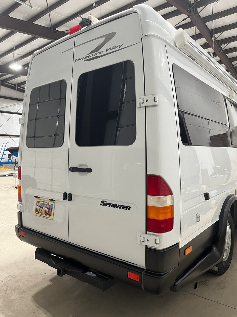 Rear view of a white Pleasure-Way Sprinter RV rental, showing tinted windows, tail lights, and a tow hitch. — photo 11