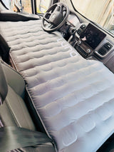 Inflatable Luno mattress fitted across the front seats of an RV rental, perfect for van camping and road trip naps.