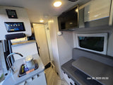 Modern rv rental interior: kitchenette with Keurig, digital control panel, dinette with wall-mounted TV.