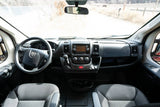Inside a comfortable RV rental: dashboard view with steering wheel, infotainment, and front seats. Ready for your adventure.