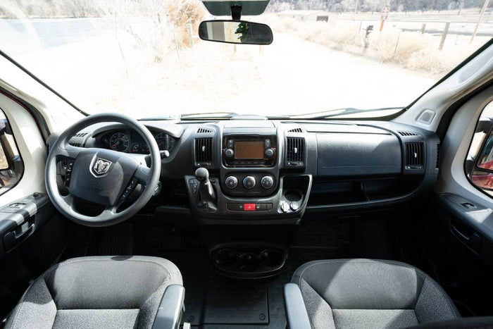 Inside a comfortable RV rental: dashboard view with steering wheel, infotainment, and front seats. Ready for your adventure.