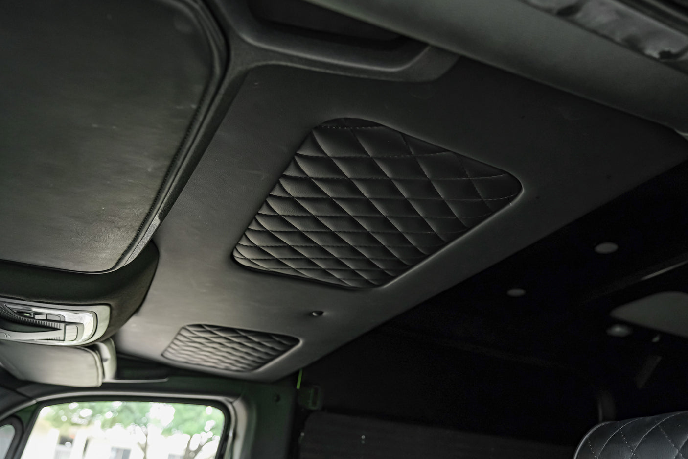Inside an RV rental: a plush, black diamond-quilted ceiling, sleek overhead console, and front visor.