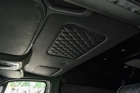 Inside an RV rental: a plush, black diamond-quilted ceiling, sleek overhead console, and front visor.