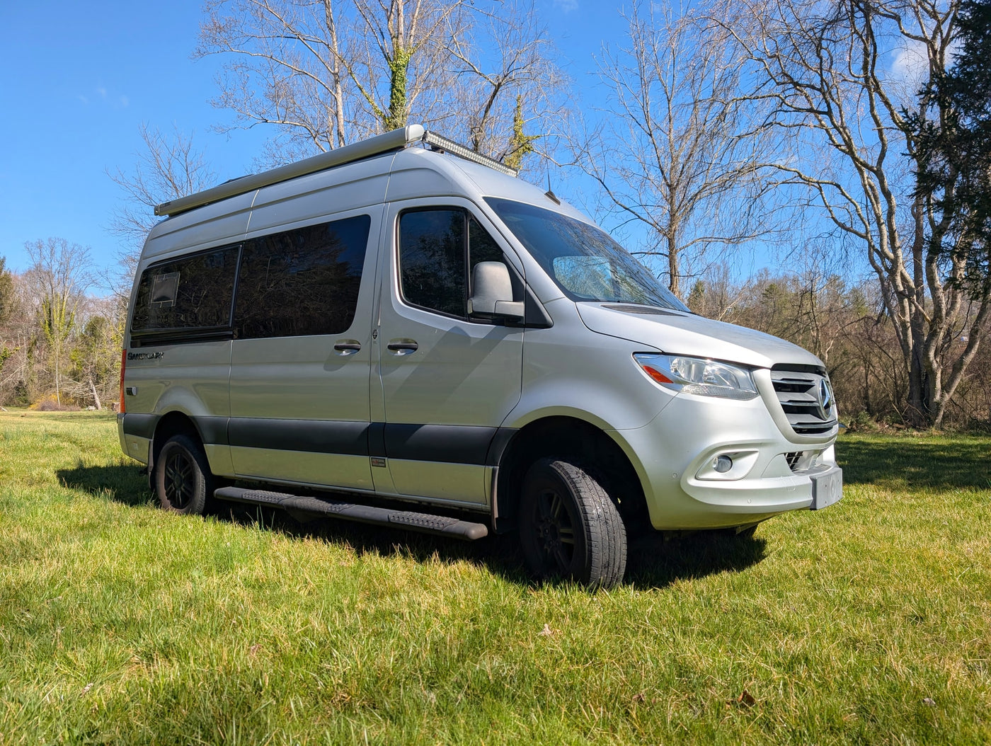  and a sunny green landscape view through the windshield.|Front view of a silver Mercedes Sprinter van — photo 7