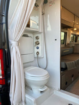 RV rental campervan wet bath: compact shower, toilet, & mirrored cabinet, ready for your adventure.