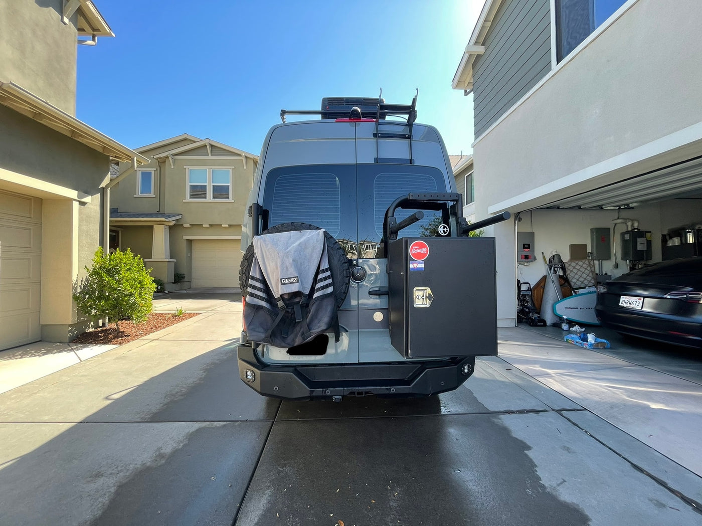 Grey custom Sprinter camper van, ideal for RV rental adventures, featuring rear storage & roof rack, parked in a sunny driveway. — photo 3
