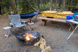 A picturesque forest campsite featuring a blazing fire, comfy hammock, and organized picnic area – ready for your RV rental trip.