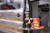 Cozy RV rental setup: wine, crackers, and fruit on a pull-out table for an outdoor picnic experience.