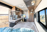 Experience comfort in this cozy RV rental's versatile interior, featuring a compact kitchen, bed, and scenic views.