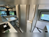 Explore this compact RV rental interior featuring a kitchenette, dining table, and cozy bench seating for travel comfort.