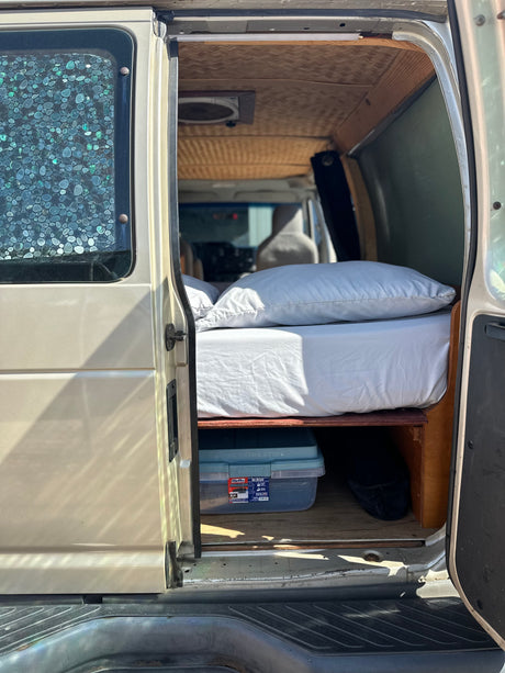 Cozy RV rental interior: bed, under-bed storage, bamboo ceiling. Perfect for your van life adventure.