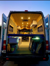 Spacious custom RV rental interior, seen from the rear. Features wood ceiling, kitchen, and ample storage.