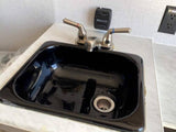 RV rental interior: A black sink with chrome faucet, white countertop, and wall-mounted controls.