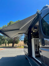 Open RV rental with extended awning, revealing its compact interior for outdoor adventures under a clear blue sky.