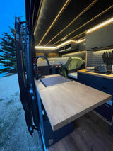 Inside this rv rental, a modern camper van offers a full kitchen, comfy bed, and ambient lighting, perfect for mobile adventures.