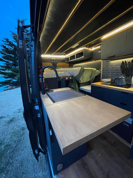 Inside this rv rental, a modern camper van offers a full kitchen, comfy bed, and ambient lighting, perfect for mobile adventures.