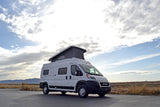 White Solis pop-top rv rental van parked in a scenic outdoor setting, ready for adventure.
