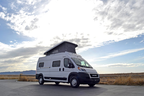 White Solis pop-top rv rental van parked in a scenic outdoor setting, ready for adventure.