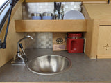 Compact RV rental kitchen with a small sink, coffee, and essential shelf storage for your adventures.