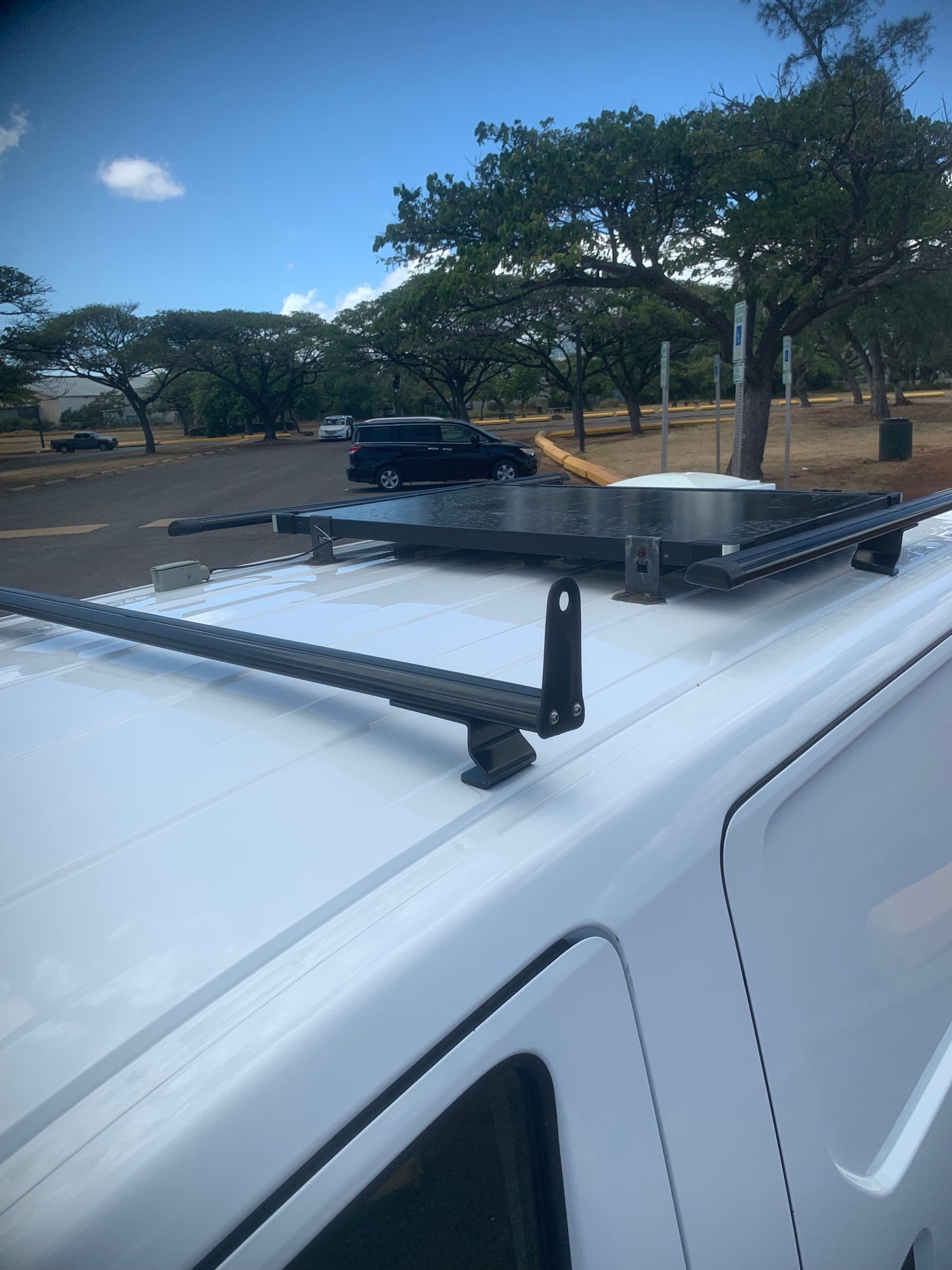 White RV rental van with a roof rack system, parked under a clear sky.