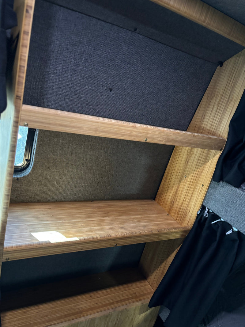 RV rental interior showcases custom multi-tiered bamboo storage shelves, ideal for organized camper living. — photo 16