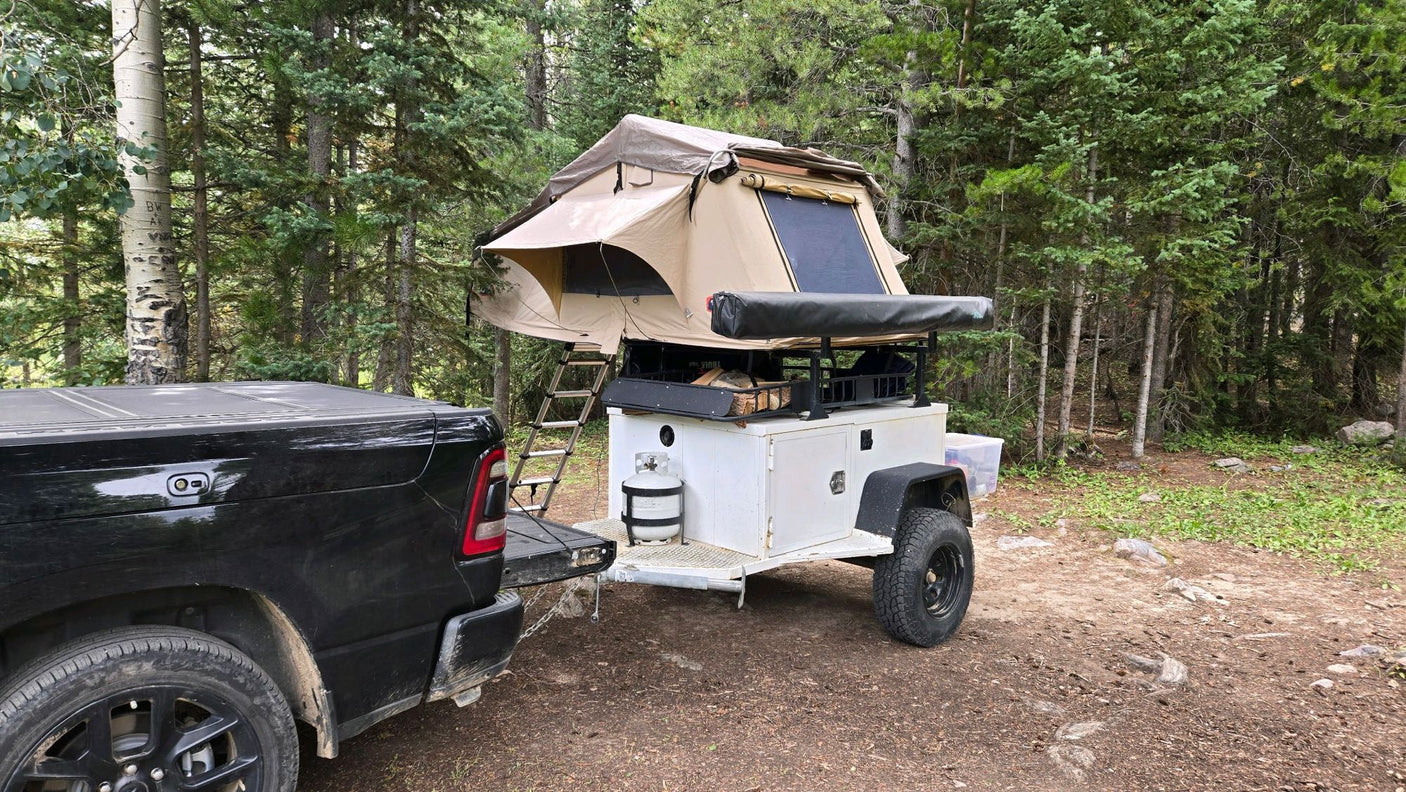 Off-road camping setup with a pickup truck & trailer, featuring a deployed rooftop tent. A unique alternative to an rv rental.