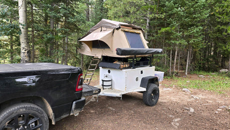 Off-road camping setup with a pickup truck & trailer, featuring a deployed rooftop tent. A unique alternative to an rv rental.