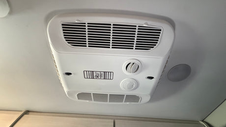 RV rental essential: Ceiling AC unit featuring Coleman-Mach thermostat control, vents, and comfort knobs for a pleasant journey.