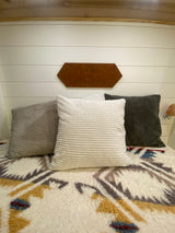 Comfortable RV bedroom featuring corduroy pillows, a patterned blanket, and "Living the Good Life" decor. Ideal for rv rental stays.