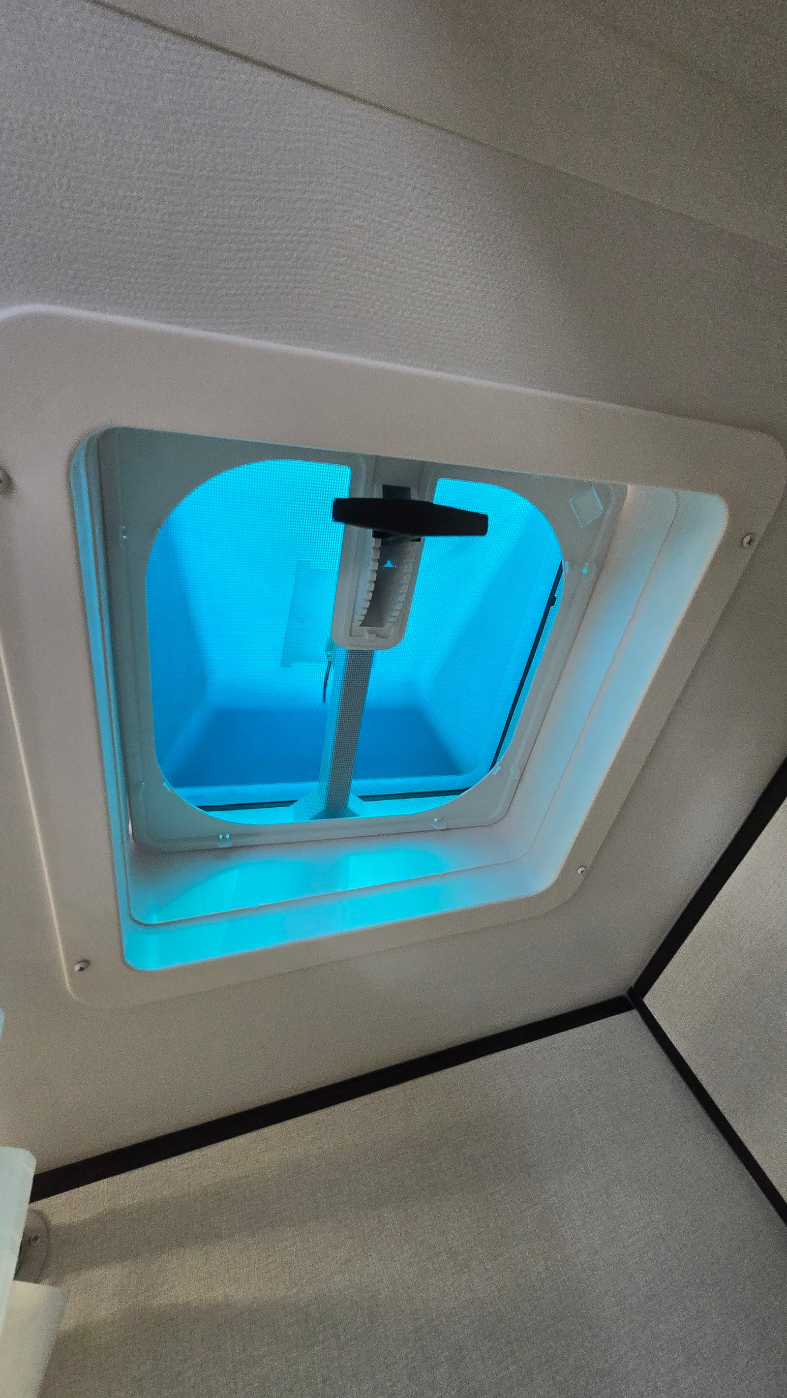 Inside an RV rental: a bright blue ceiling vent/skylight with a control handle and screen visible.