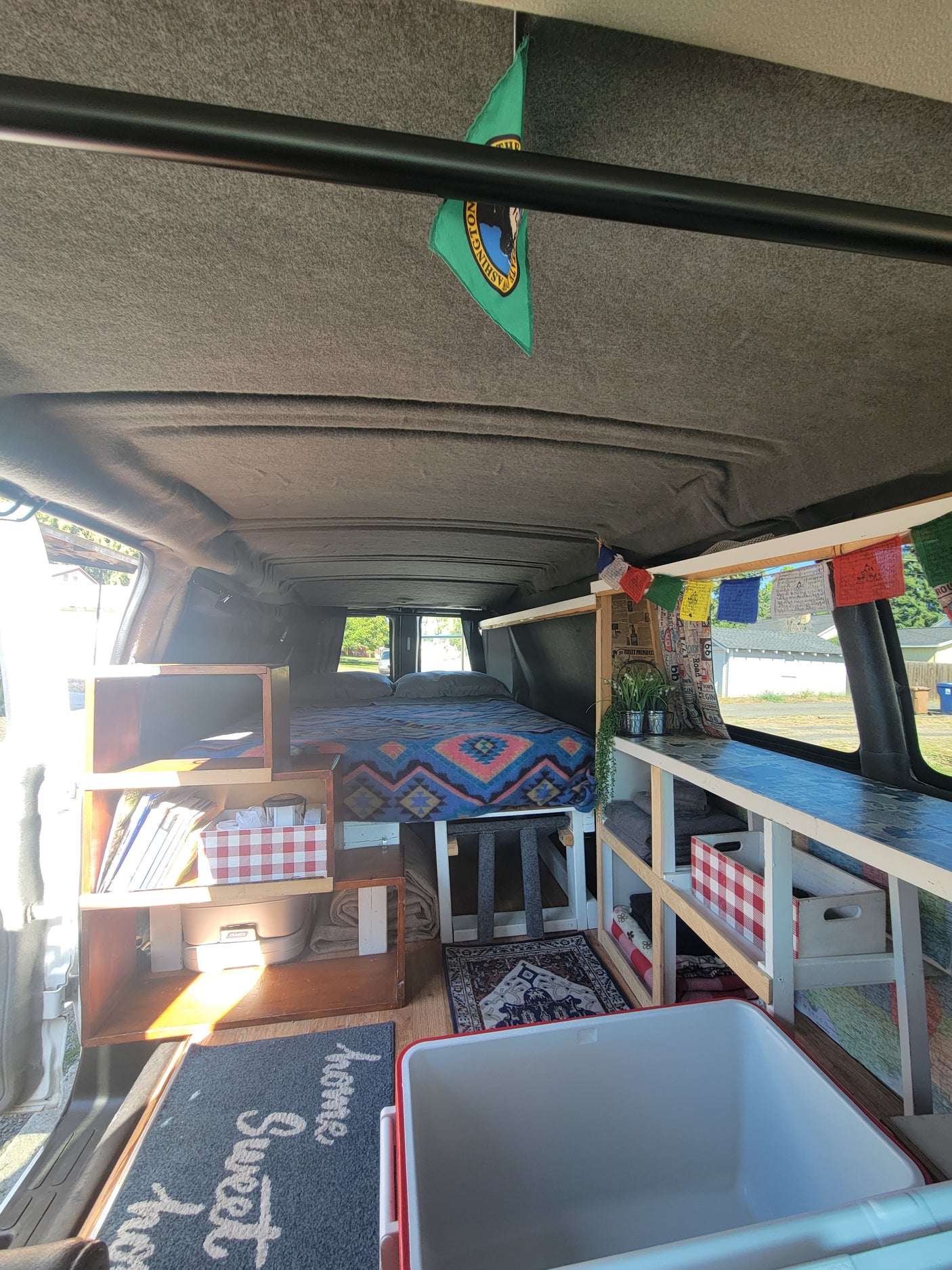 Explore this cozy RV rental van conversion interior with a comfy bed, storage, and compact living area.