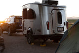 Ready for adventure! A silver Airstream travel trailer, SUV, and tent at a sunlit campsite. Great RV rental option!