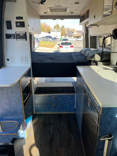 Cozy rv rental interior: bed, kitchenette, and controls clearly visible, perfect for your next adventure.