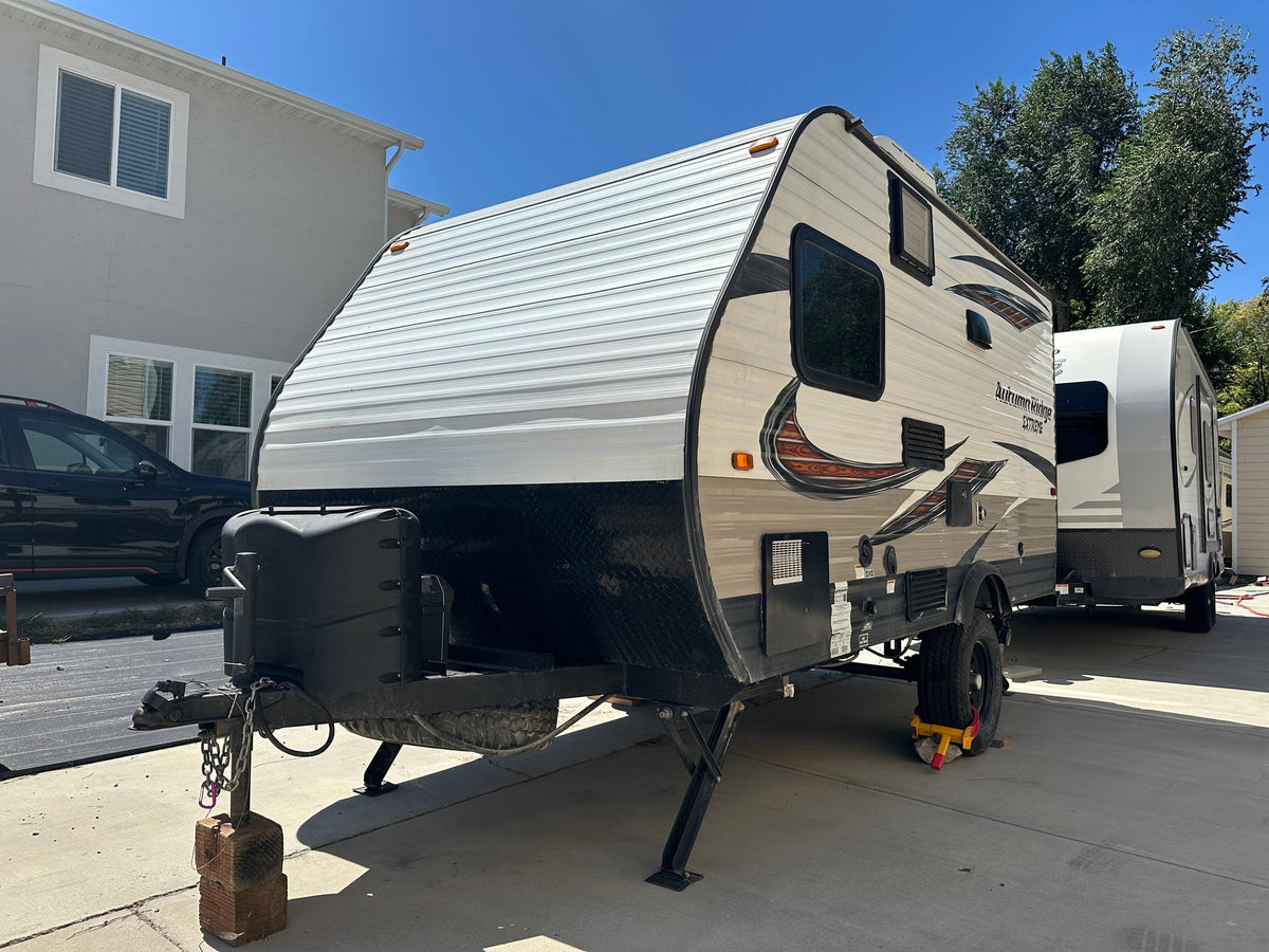 Two travel trailers, the foreground one a clean RV rental, parked on a sunny driveway, ready for adventures. — photo 3