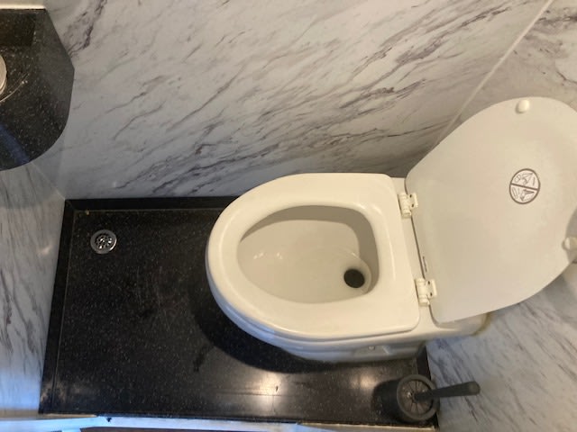  and a unique hexagonal table.|Spacious RV rental interior: two-tier setup with lower carpeted cargo area holding a broom and hose