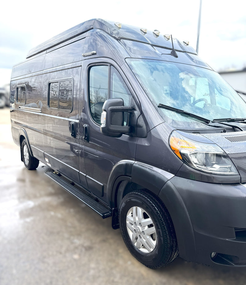 This dark gray RV rental camper van, glistening with raindrops, is parked outdoors, ready for your next road trip adventure. — photo 4