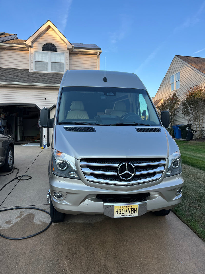 Front view of a beige Mercedes-Benz Sprinter RV, likely an RV rental, parked on a driveway in front of a house under clear skies. — photo 19