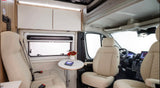 Spacious and bright RV rental interior with cream seating, a small dining table, storage, and the driver's cockpit.