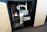 RV rental's compact plumbing, water pump, and waste holding tank with a small bin, efficiently organized within a cabinet.