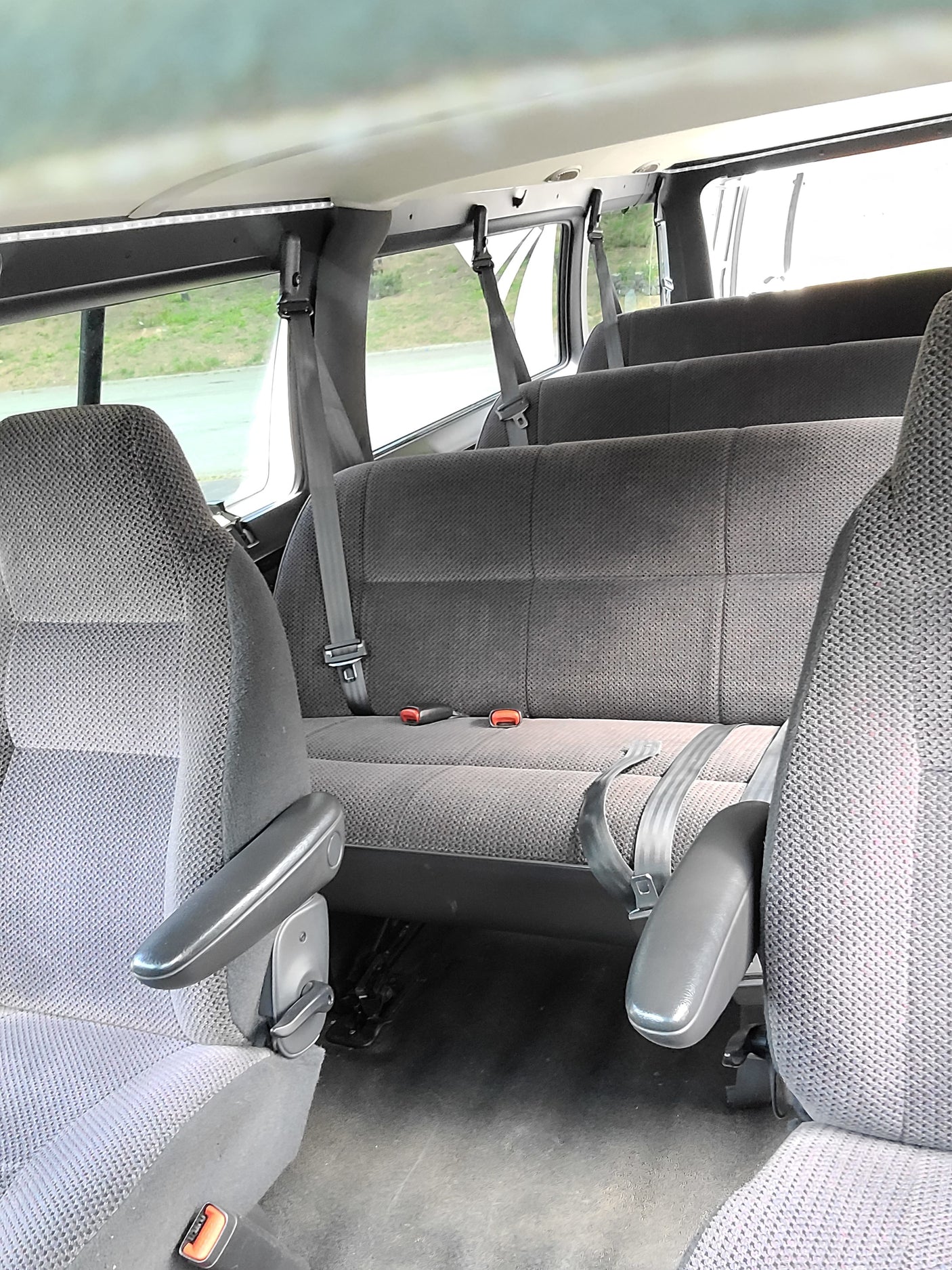 RV rental interior with multiple rows of gray cloth seats, seatbelts, and an overhead LED light strip.