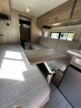 Well-appointed RV rental interior: versatile lounge/dining, compact kitchen, cozy bed. Your next adventure awaits!