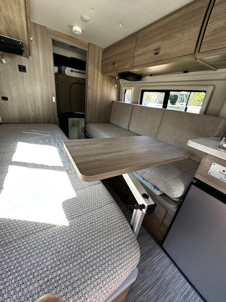 Well-appointed RV rental interior: versatile lounge/dining, compact kitchen, cozy bed. Your next adventure awaits!