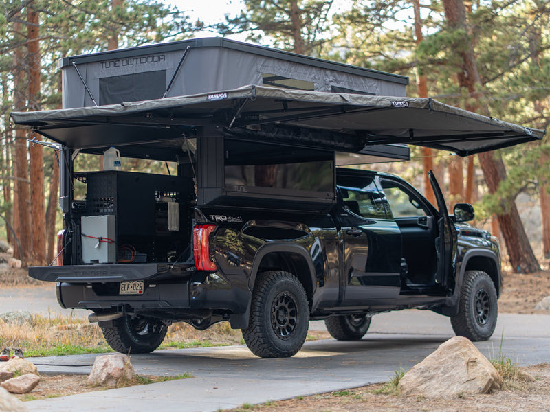  perfect for an rv rental outdoor adventure.|Black Toyota Tundra overland rig with Tune Outdoor rooftop tent & Taruca awning. An ideal RV rental for wilderness camping.|An organized Tune truck camper interior — photo 3