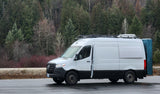 White Mercedes Sprinter camper van, a great RV rental, parked in a forest. Equipped for adventure travel.