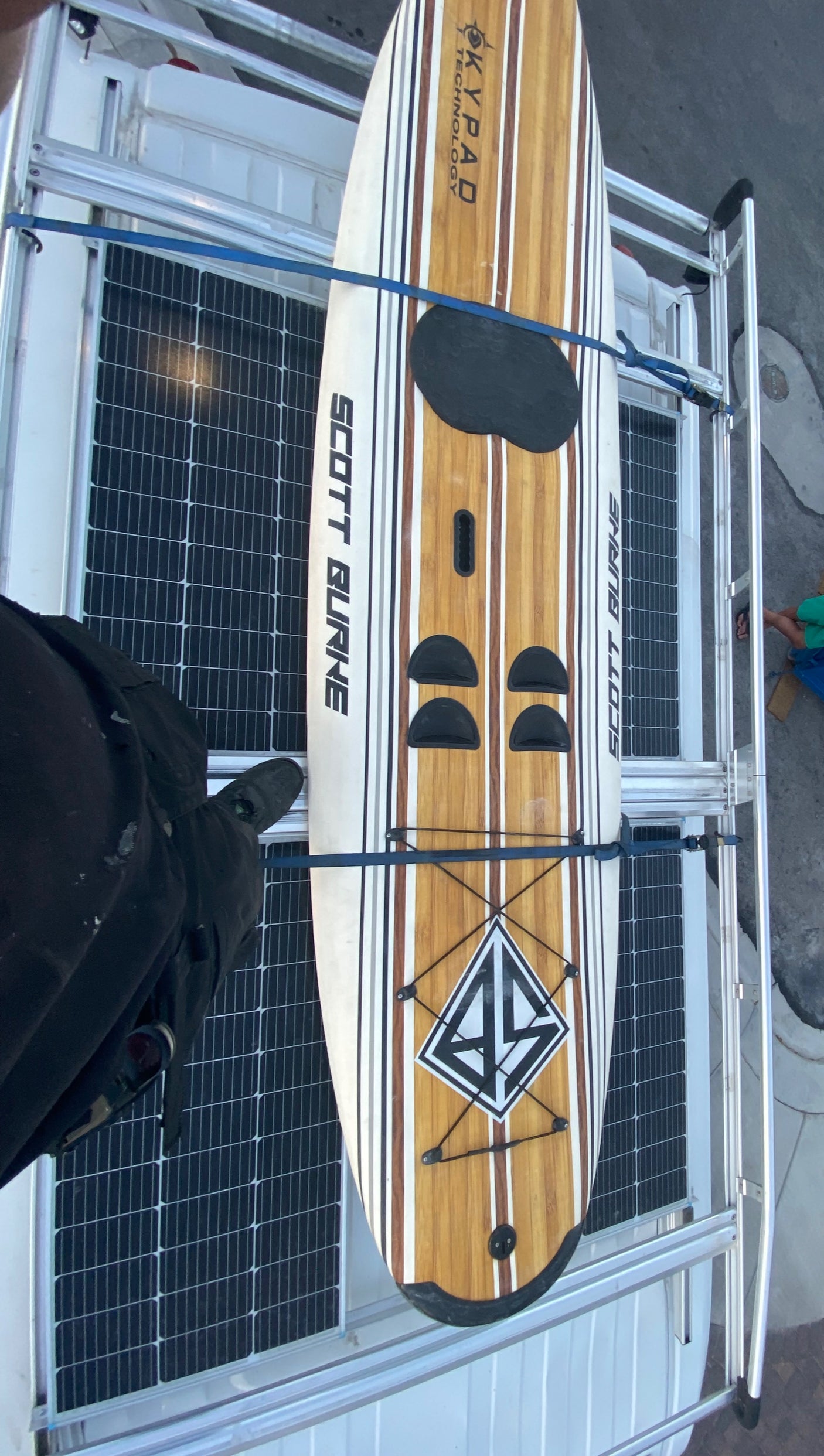 An RV rental with a Scott Burke paddleboard and solar panels on its roof rack. Perfect for outdoor adventures.